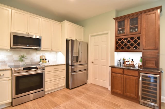 kitchen with appliances with stainless steel finishes, beverage cooler, light hardwood / wood-style flooring, and decorative backsplash