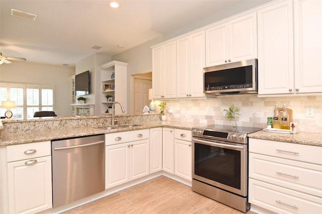 kitchen featuring light stone countertops, appliances with stainless steel finishes, sink, white cabinetry, and ceiling fan