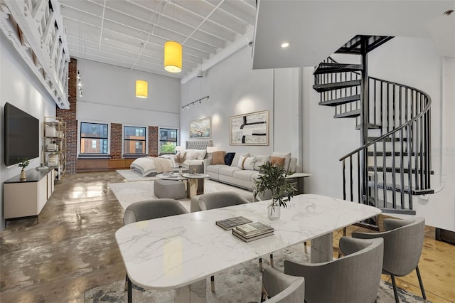 dining space with a towering ceiling and concrete floors