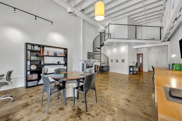 dining room featuring a towering ceiling and concrete flooring