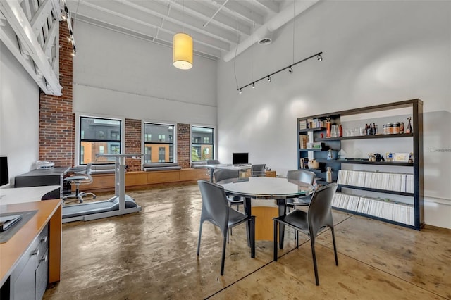 dining space with beamed ceiling, a towering ceiling, and concrete flooring