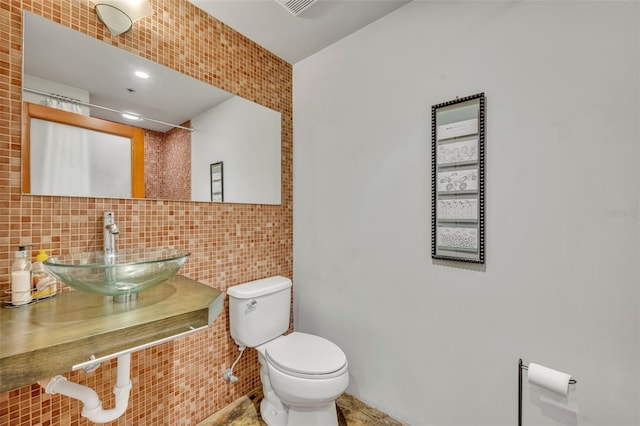 bathroom featuring sink, tile walls, backsplash, and toilet