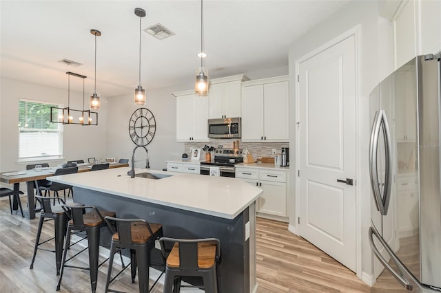 kitchen featuring white cabinets, pendant lighting, stainless steel appliances, and sink