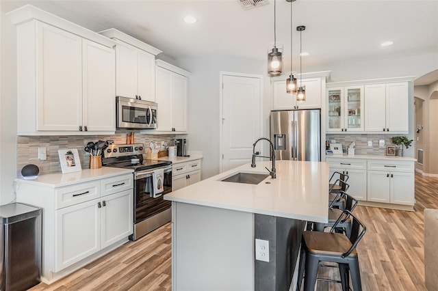 kitchen with light hardwood / wood-style flooring, stainless steel appliances, a center island with sink, and sink