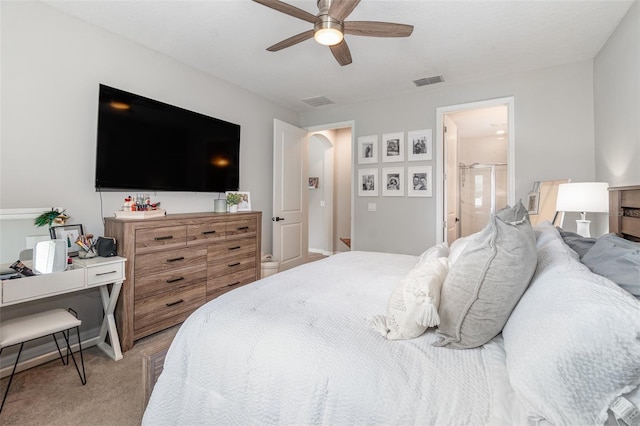 bedroom featuring light colored carpet, ceiling fan, and connected bathroom