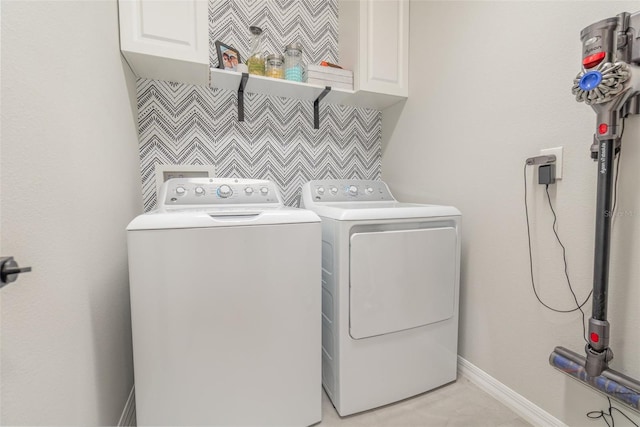 laundry room with washing machine and clothes dryer and cabinets