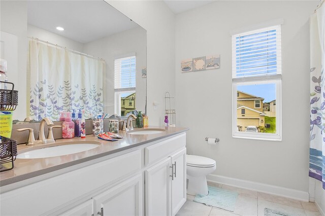 bathroom with a wealth of natural light, vanity, toilet, and tile patterned flooring