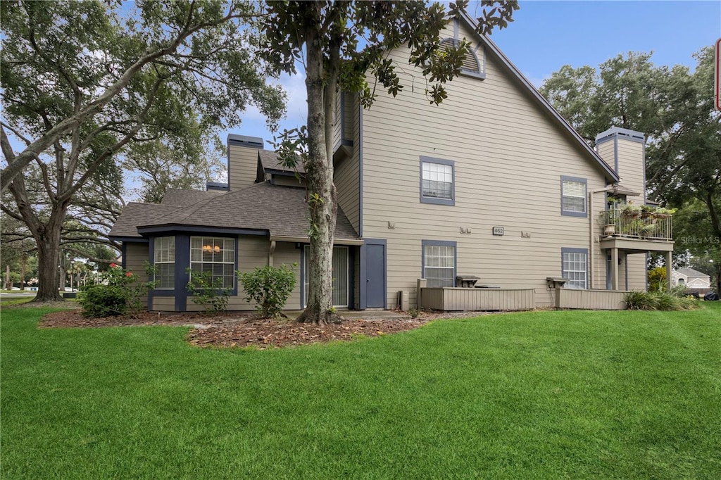 back of house with a balcony and a yard