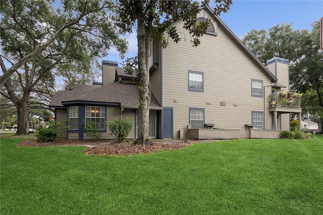 back of house with a balcony and a yard