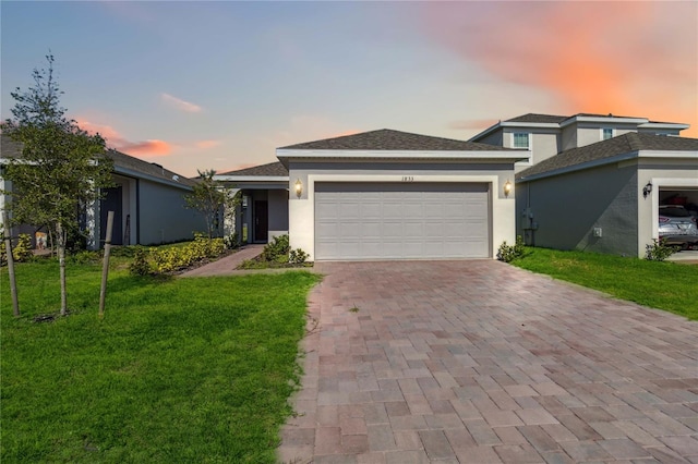 view of front of home featuring a front yard, decorative driveway, a garage, and stucco siding