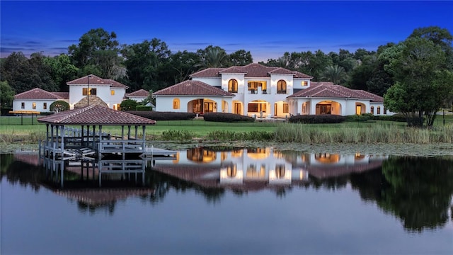 rear view of house with a water view, boat lift, fence, and a lawn