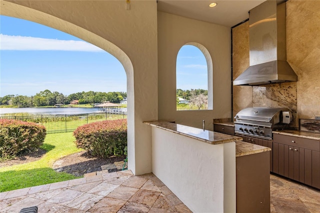 view of patio / terrace featuring a water view, fence, an outdoor kitchen, and area for grilling