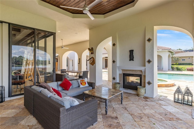 view of patio / terrace with an outdoor living space with a fireplace, a pool with connected hot tub, and a ceiling fan