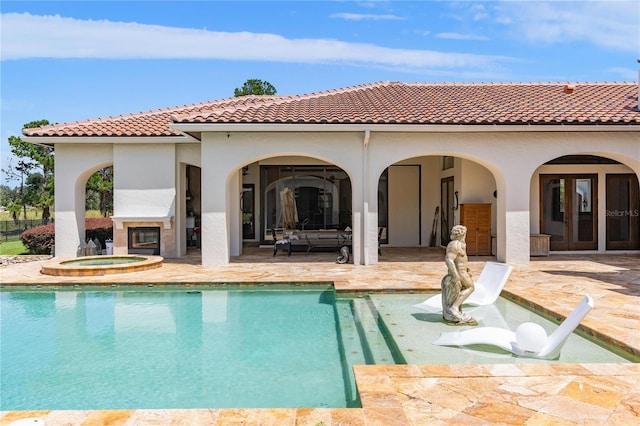 rear view of property with a fenced in pool, a fireplace, a patio, stucco siding, and an in ground hot tub