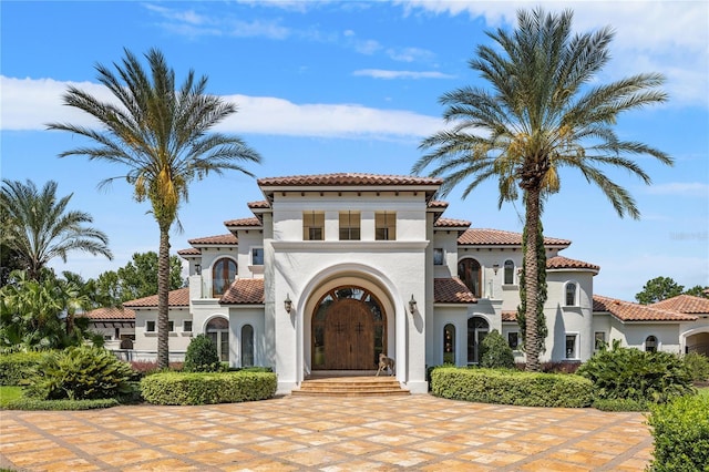 mediterranean / spanish house featuring a tile roof and stucco siding