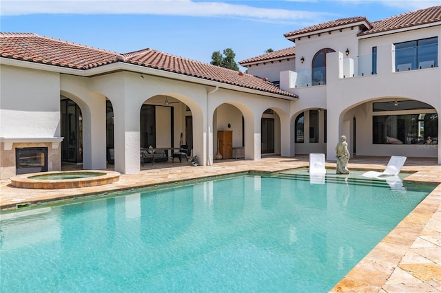 back of house featuring an outdoor pool, a patio, a tiled roof, an in ground hot tub, and stucco siding