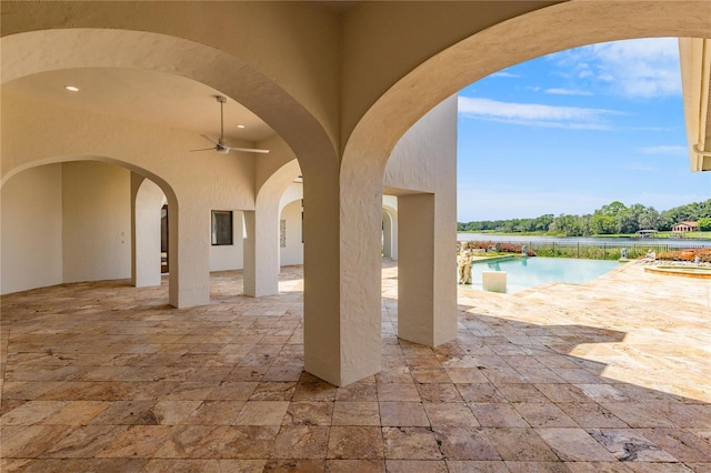 view of patio / terrace with a water view, an outdoor pool, and a ceiling fan