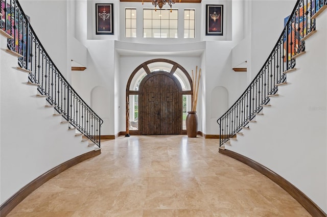 entryway featuring a towering ceiling, stairs, and baseboards