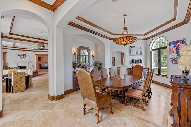 dining space featuring a wealth of natural light, a tray ceiling, a fireplace, and baseboards