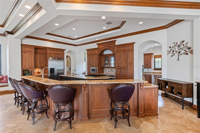 kitchen featuring a spacious island, arched walkways, stainless steel appliances, and a kitchen bar