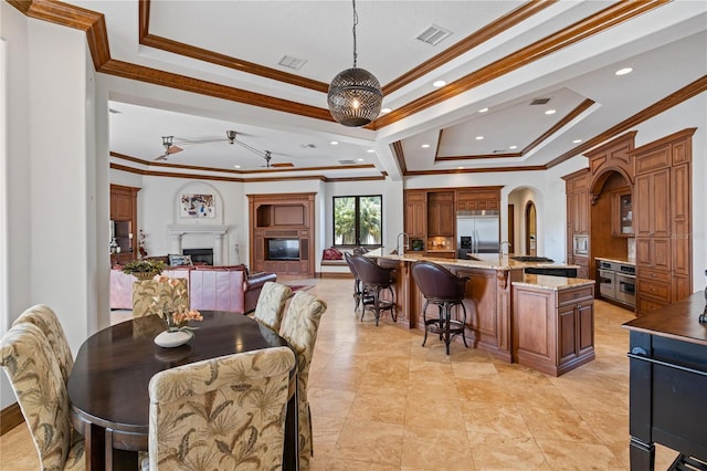 dining room with crown molding, a tray ceiling, visible vents, and a fireplace