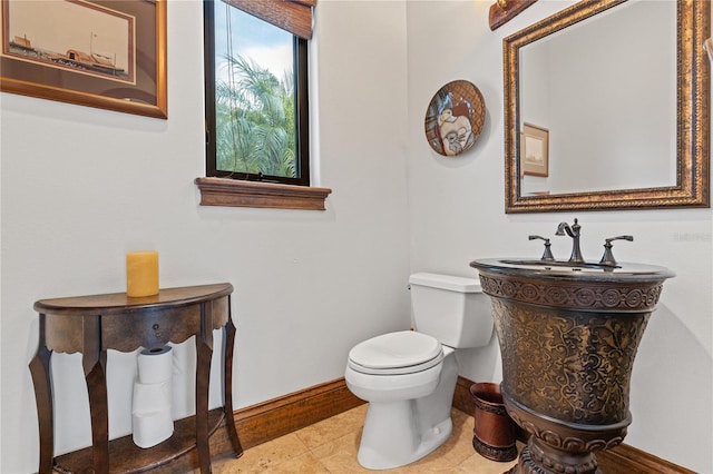 half bathroom with baseboards, toilet, and tile patterned floors