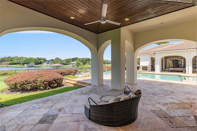 view of patio / terrace featuring ceiling fan, a water view, fence, and a fenced in pool