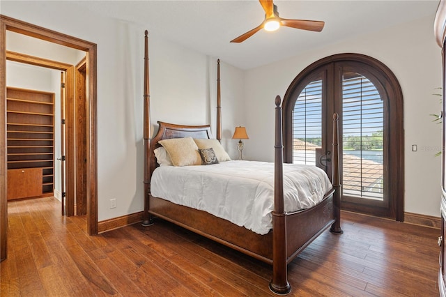 bedroom with dark wood-style floors, a walk in closet, ceiling fan, access to outside, and baseboards