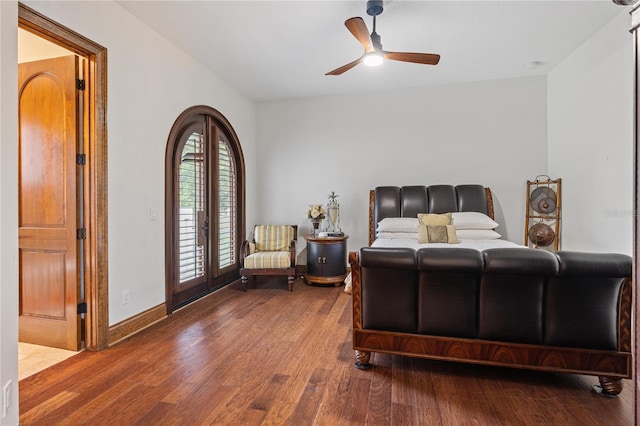 bedroom with access to outside, french doors, arched walkways, and wood finished floors