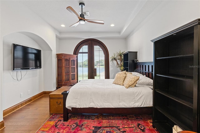 bedroom featuring baseboards, dark wood finished floors, a tray ceiling, and recessed lighting