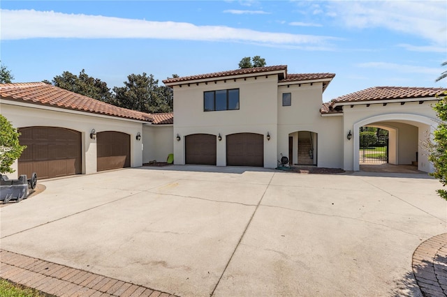 mediterranean / spanish house with driveway, a tiled roof, and stucco siding