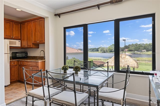 dining space with a water view, crown molding, and baseboards