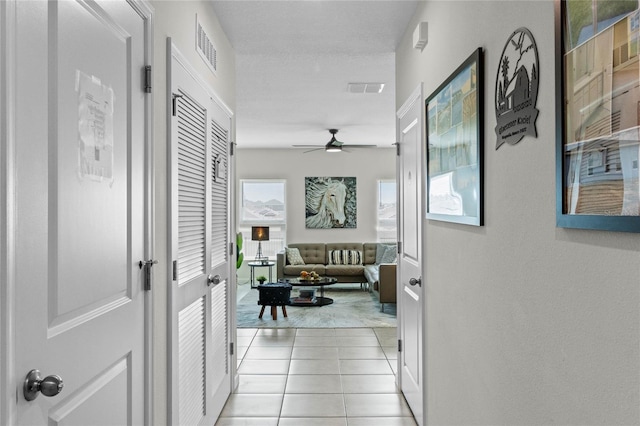 corridor with a textured ceiling and light tile patterned floors