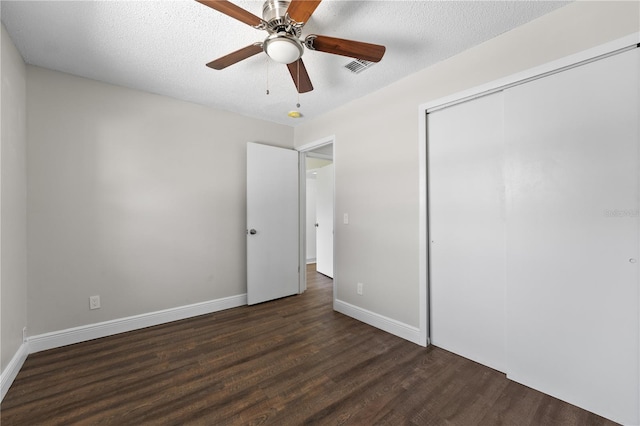 unfurnished bedroom with a textured ceiling, dark wood-type flooring, ceiling fan, and a closet