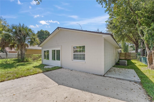 view of side of home with a yard, a patio area, and central air condition unit