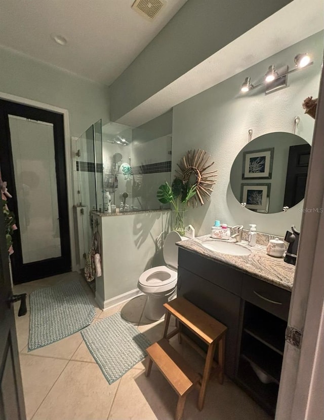 bathroom with tile patterned flooring, walk in shower, toilet, and vanity