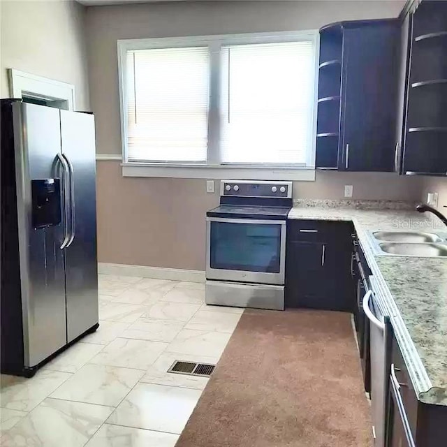 kitchen featuring appliances with stainless steel finishes, light stone countertops, and sink