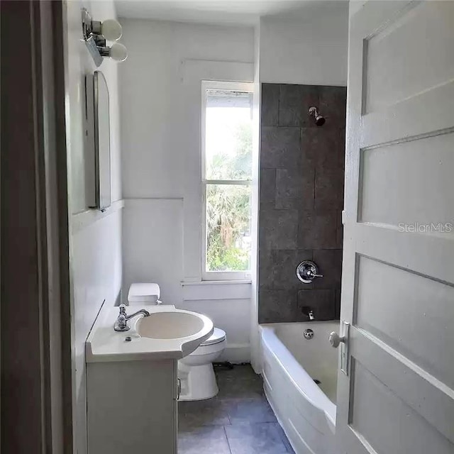 full bathroom featuring tiled shower / bath, vanity, toilet, and tile patterned floors