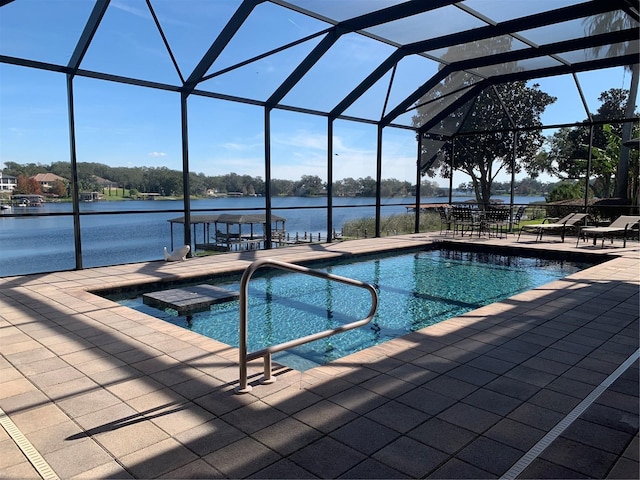 view of pool featuring glass enclosure, a water view, a patio, and a jacuzzi