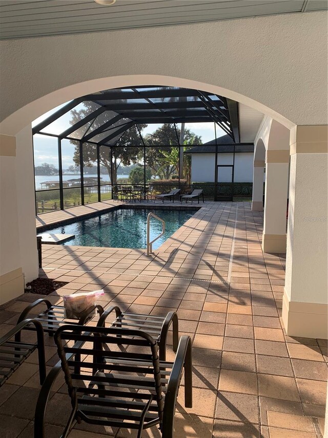 view of swimming pool with glass enclosure and a patio