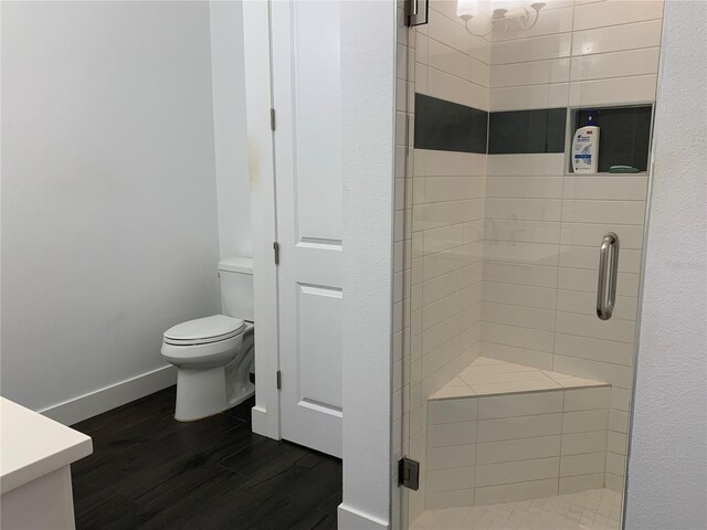 bathroom with hardwood / wood-style floors, vanity, toilet, and a shower with door