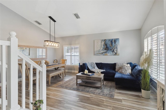 living room with plenty of natural light, light hardwood / wood-style floors, and vaulted ceiling