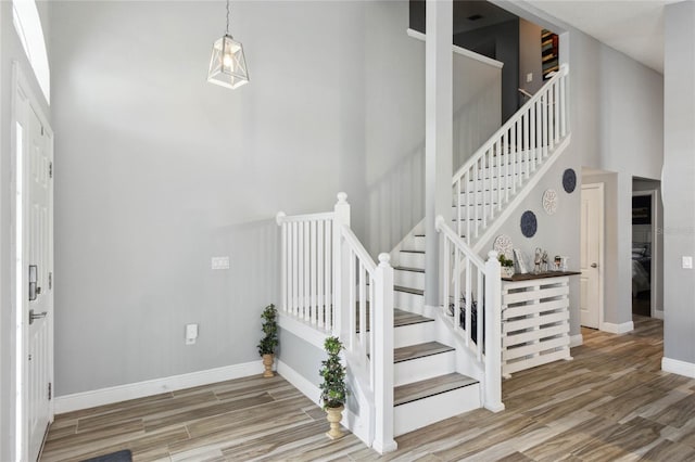 staircase featuring wood-type flooring and a towering ceiling