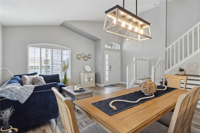 dining space with wood-type flooring and high vaulted ceiling