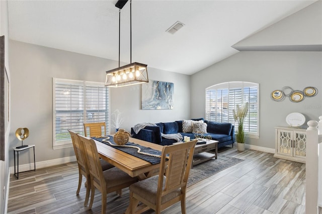 dining space featuring lofted ceiling, light wood-type flooring, and a chandelier