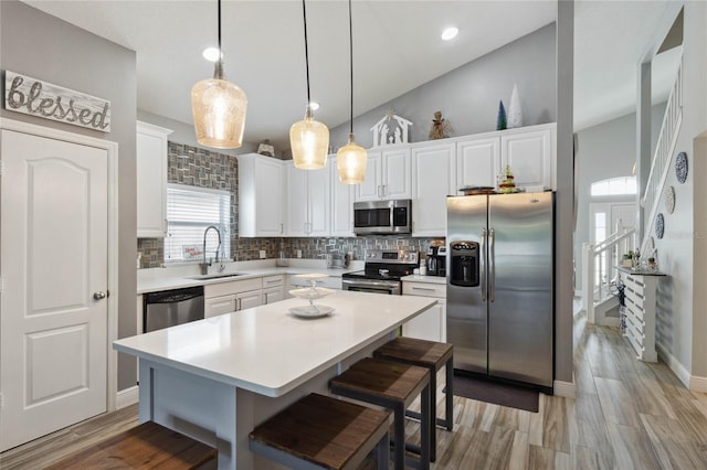 kitchen featuring a kitchen island, a breakfast bar area, sink, hanging light fixtures, and appliances with stainless steel finishes