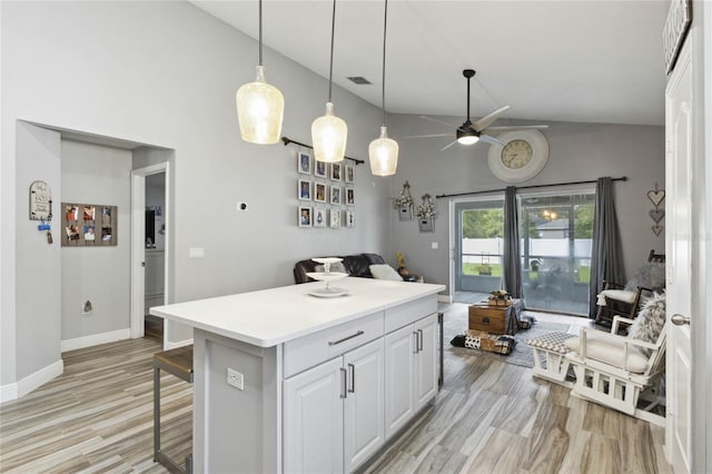 kitchen with ceiling fan, white cabinets, a kitchen island, a breakfast bar area, and light wood-type flooring