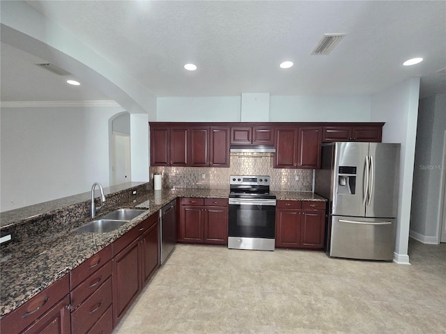 kitchen with crown molding, appliances with stainless steel finishes, sink, kitchen peninsula, and dark stone counters