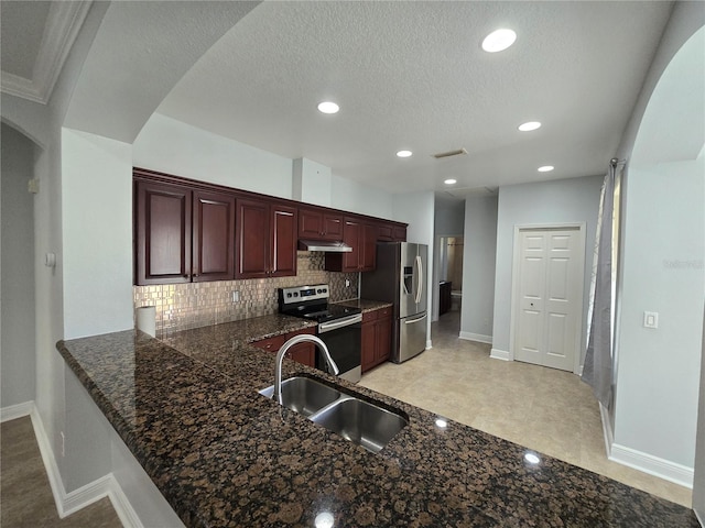 kitchen featuring appliances with stainless steel finishes, sink, kitchen peninsula, tasteful backsplash, and a textured ceiling