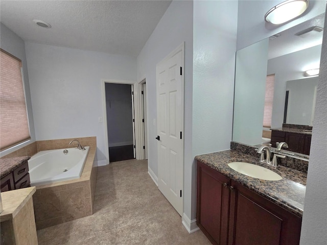 bathroom featuring vanity, a textured ceiling, and a relaxing tiled tub